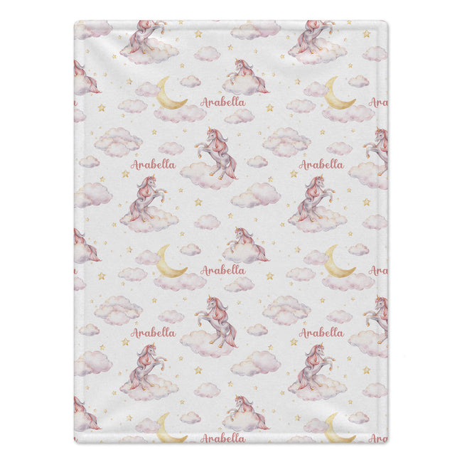 Personalized Unicorn Baby Girl Blanket. Dreamy unicorns, blush clouds, golden moons, and little stars surround a custom name on a white background.