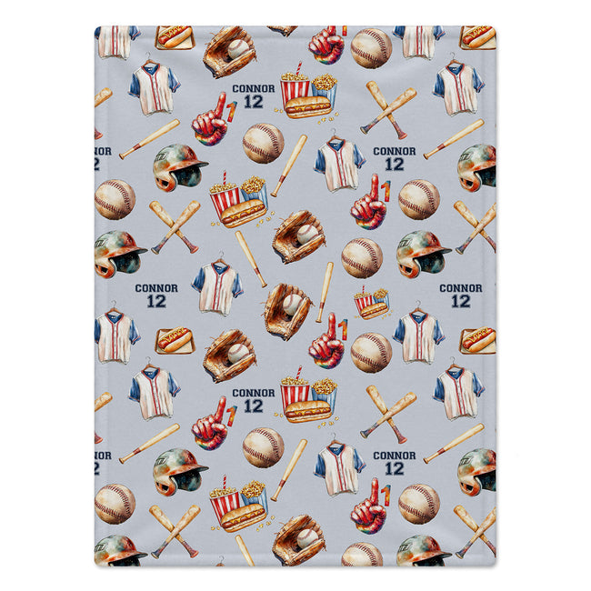 A personalized blanket with a repeating baseball-themed print on a light gray background. The pattern includes baseball bats, baseballs, baseball uniforms, helmets, a glove, a popcorn bucket, and the name 'CONNOR 12' repeated.