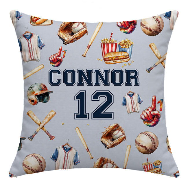 A square throw pillow with a light gray background printed with a baseball-themed pattern of jerseys, bats, helmets, gloves, and popcorn. The center features the text 'CONNOR 12' in navy blue and white.