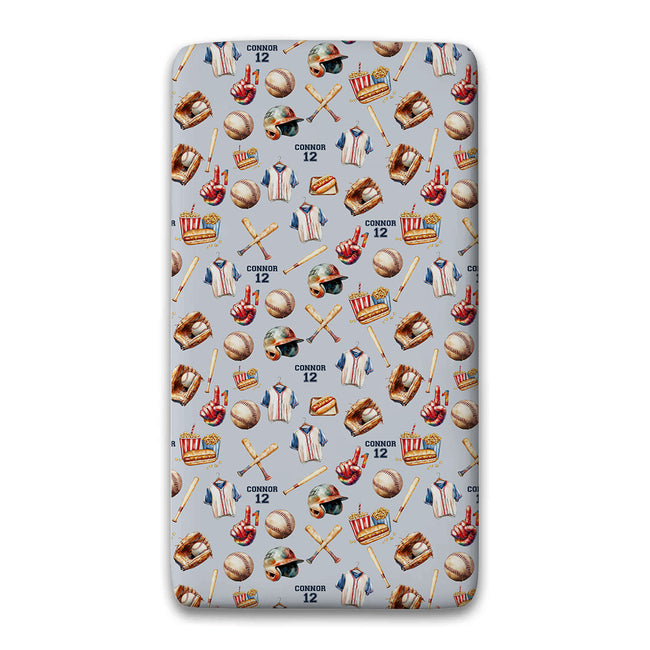 A twin fitted sheet featuring a repeating baseball-themed pattern on a light gray background. The pattern includes baseballs, bats, jerseys, gloves, helmets, and the text 'CONNOR 12'.