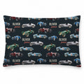 A pillowcase featuring a repeating pattern of vintage race cars in blue, green, red, and silver on a dark navy background, with the personalized text 'OLIVER james' printed in white and orange.