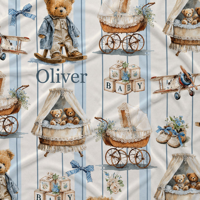 Personalized baby bedding fabric featuring a repeating pattern of teddy bears, vintage baby carriages, blocks spelling 'BABY', and small airplanes on a light blue and white striped background. The name 'Oliver' is printed in a dark blue serif font.