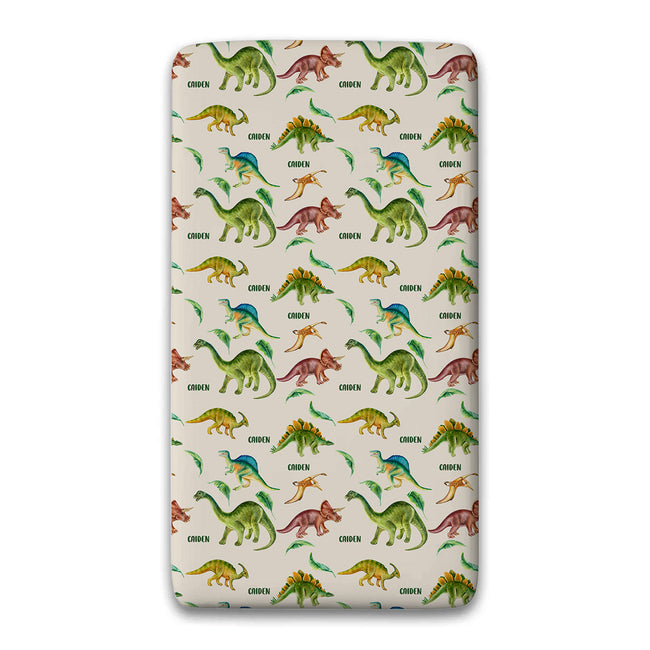 A personalized twin fitted sheet featuring a repeating pattern of colorful cartoon dinosaurs on a light beige background.