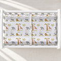Wildwood Safari changing pad cover with watercolor elephants, giraffes, lions, zebras, and the name Oliver, shown on a white changing table.