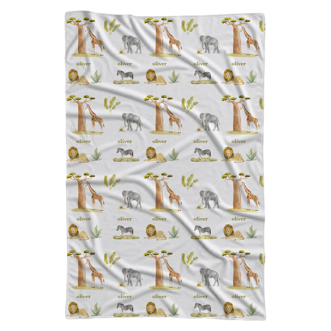 Full view of Wildwood Safari swaddle blanket with watercolor elephants, giraffes, lions, zebras, trees, and the name Oliver on white.