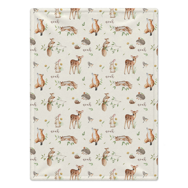 Personalized Woodland Animal Baby Blanket. Foxes, deer, rabbits, squirrels, birds, and hedgehogs surround a custom name among delicate leaves on a cream background.