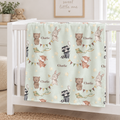 A personalized baby blanket with a woodland animal print is draped over a white crib in a bright nursery. The light mint green blanket features cartoon bears, rabbits, foxes, a raccoon, stars, and bunting, with the name 'Charlie' printed in several places.