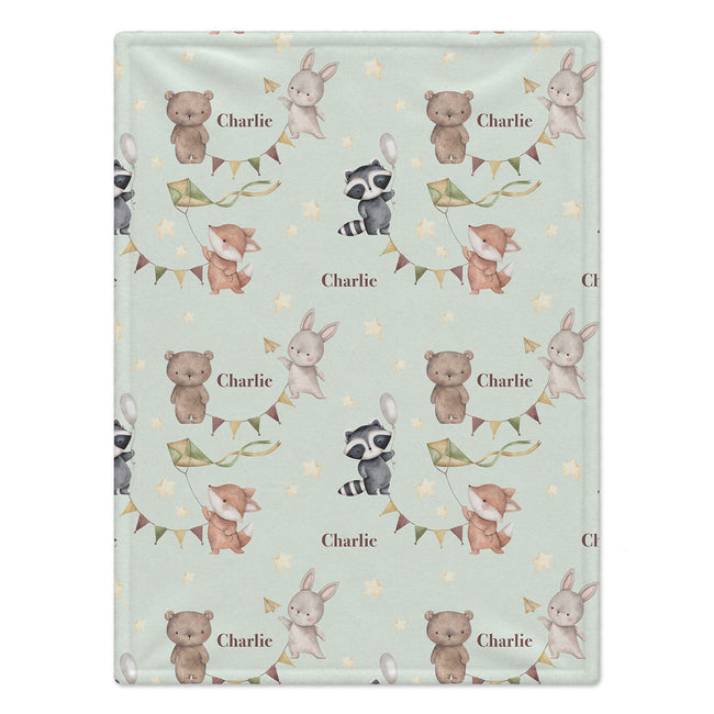 A personalized baby blanket with a repeating pattern of woodland animals (bears, rabbits, foxes, raccoons) flying balloons, decorated with bunting and stars, and customized with the name 'Charlie' in brown text.