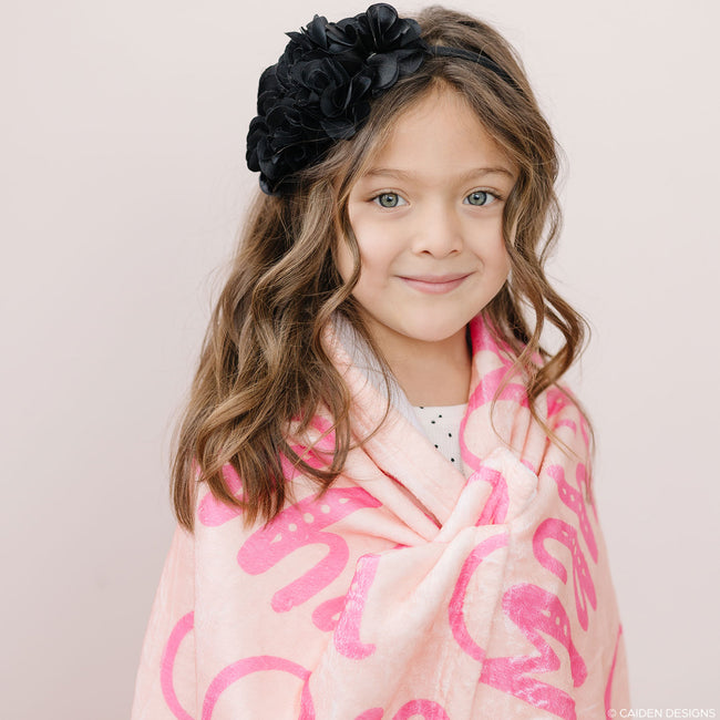 A little girl with a peach personalized blanket for kids with names on it