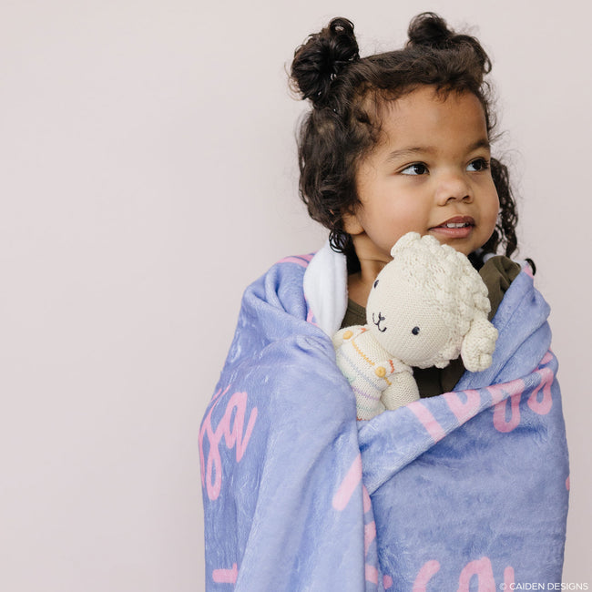 little girl with a lamb toy and a lavender personalized blanket
