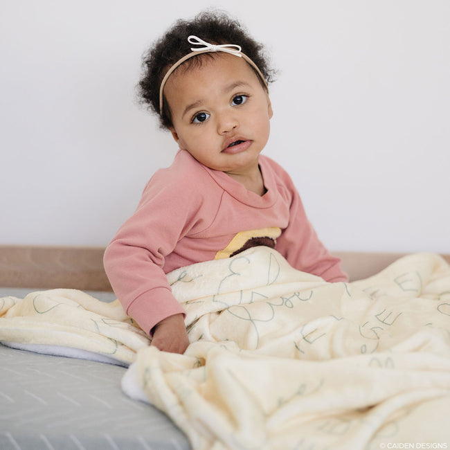 A little girl with a soft, plush personalized baby blanket with names