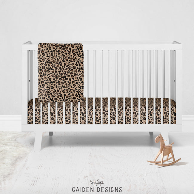 Brown leopard print crib sheet on a white crib with a matching baby blanket draped over the rail