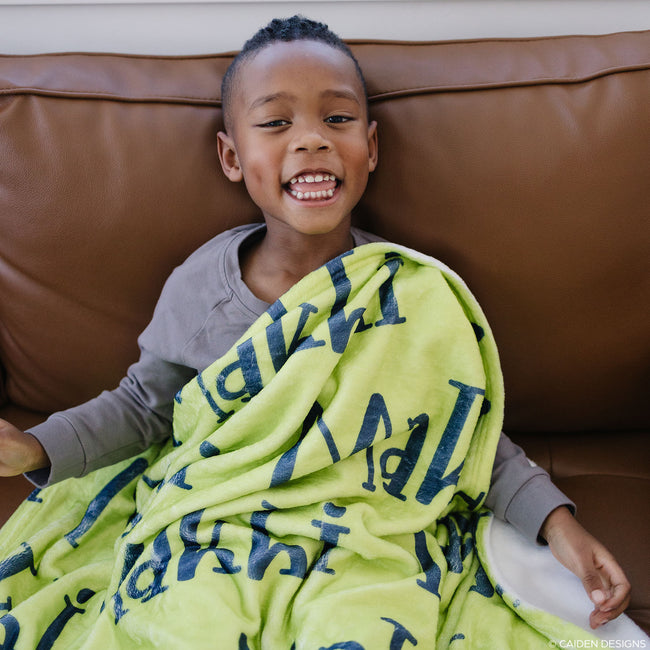 Little boy with a lime green personalized blanket with navy name on it