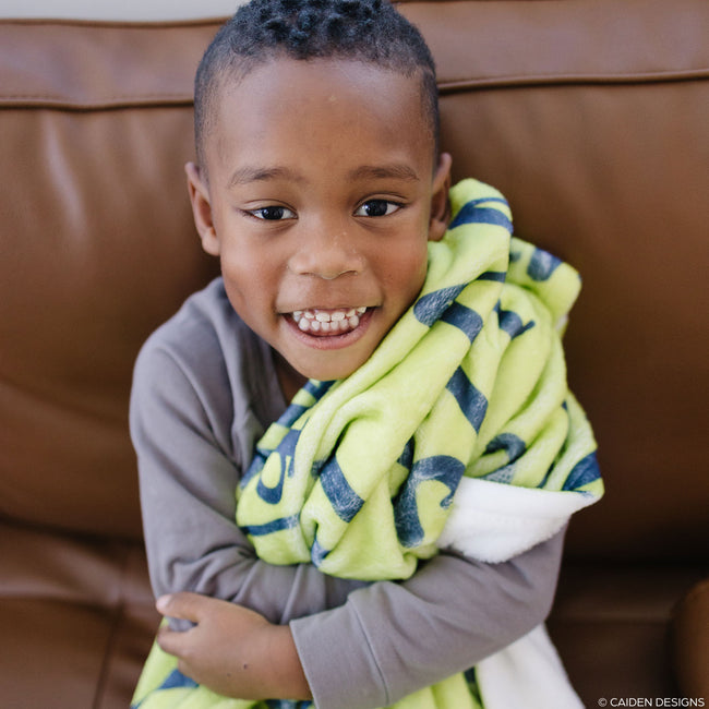 Little boy with a lime green personalized blanket with navy name on it