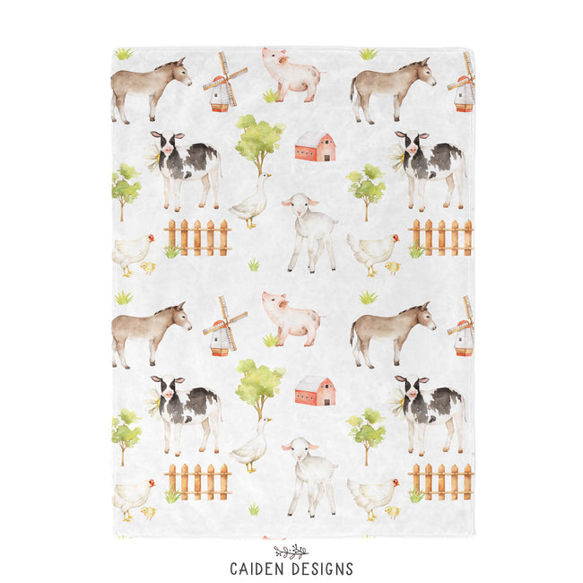A baby blanket with farm animal designs, including a sheep, cow, and pig.