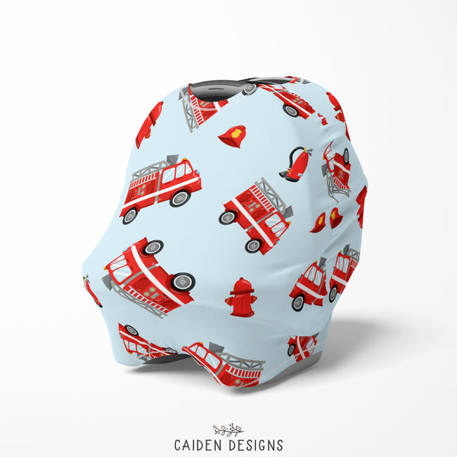A baby car seat cover featuring red fire trucks on a light blue background 