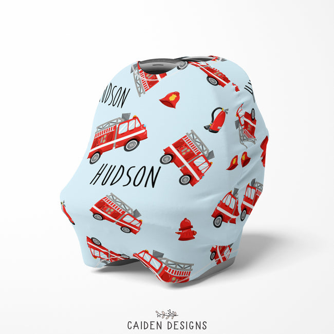 A personalized baby car seat cover featuring red fire trucks on a light blue background 