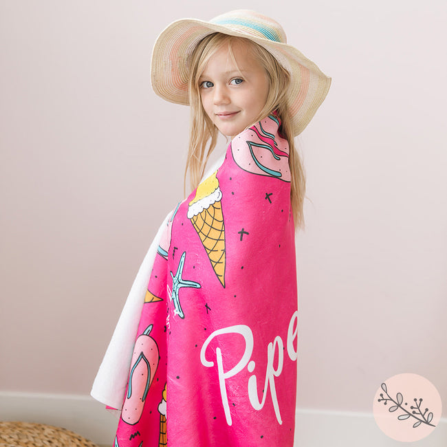 A little girl wrapped in a personalized beach towel featuring a flip flops and ice cream design.