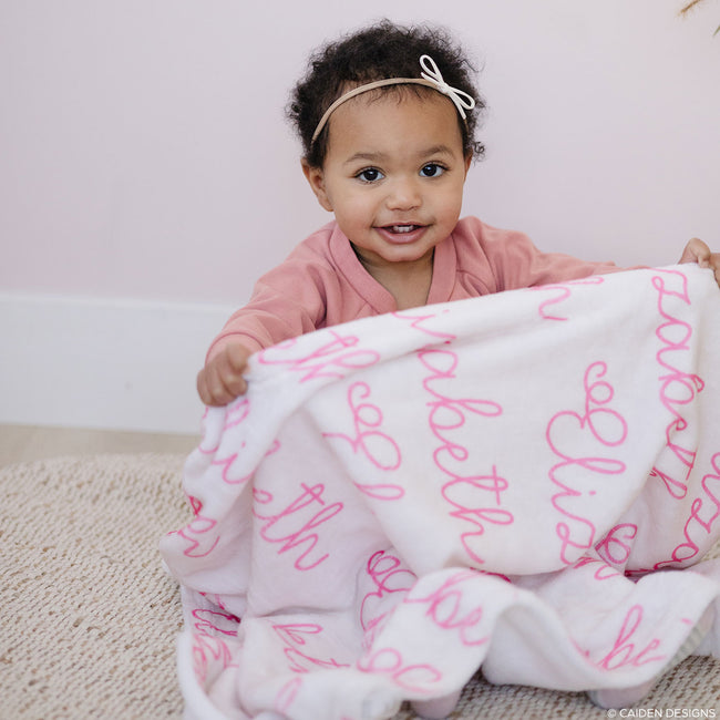 Little girl with a blush personalized blanket with pink name Elizabeth on it