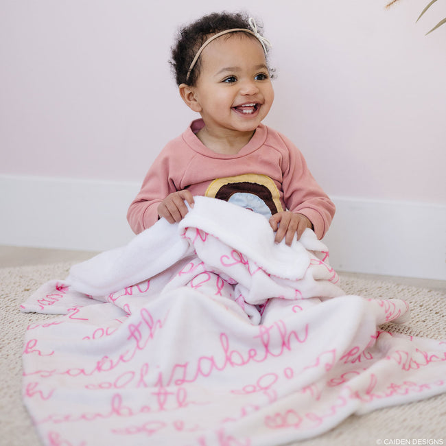 little girl with a blush personalized blanket and pink letters