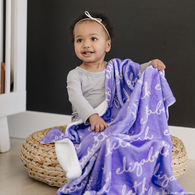 A child with a lilac personalized blanket with the name 'Elizabeth' printed on it.