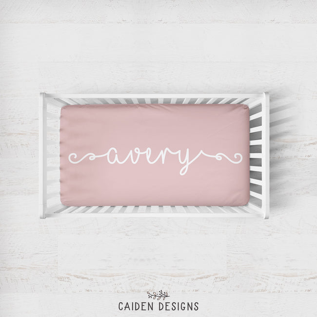 A personalized crib sheet with the name 'Avery' printed in a cursive script on a crib