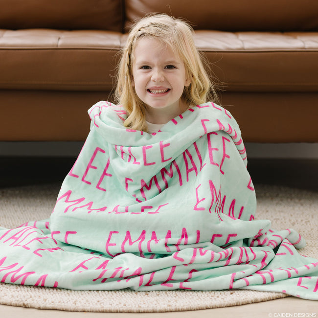 A girl with bright mint personalized blanket with hot pink letters
