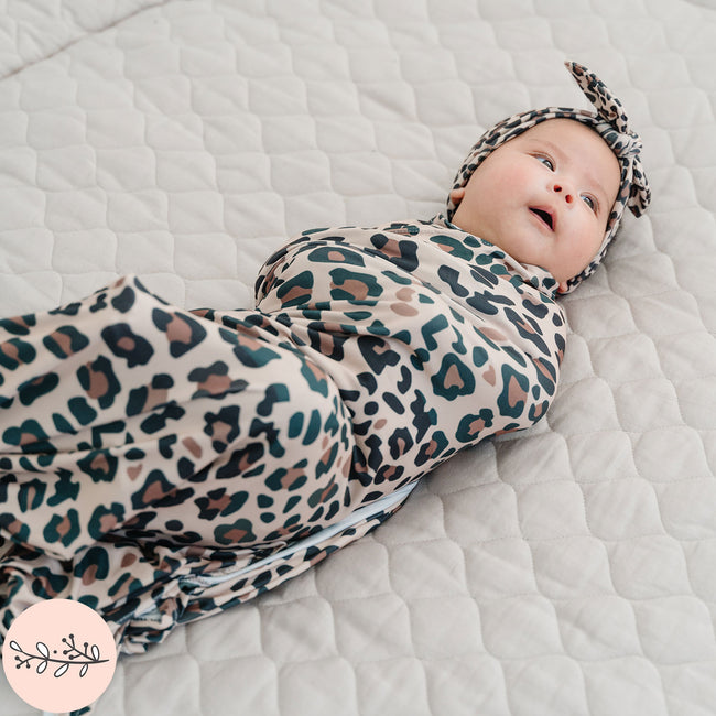 A baby swaddle blanket with brown leopard print design