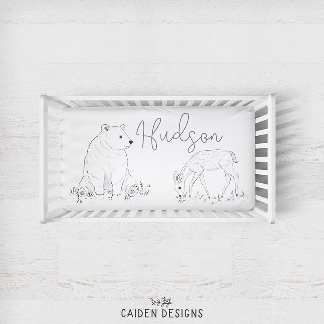 A personalized crib sheet with the name 'Hudson' printed on it, featuring a watercolor illustration of a bear and a deer.