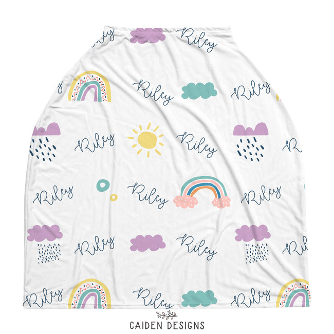 A multi-use baby car seat cover with a white background featuring colorful rainbow and cloud illustrations, with the name 'Riley' prominently displayed.
