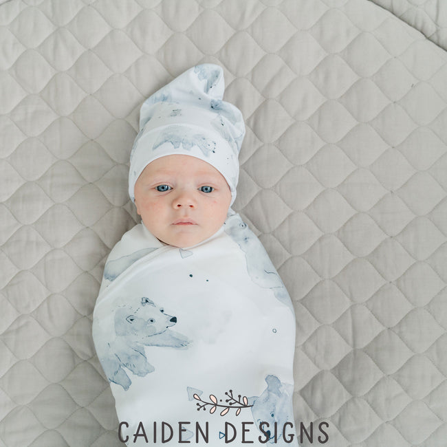 A baby wrapped in a monochrome watercolor polar bear swaddle blanket with a matching baby hat