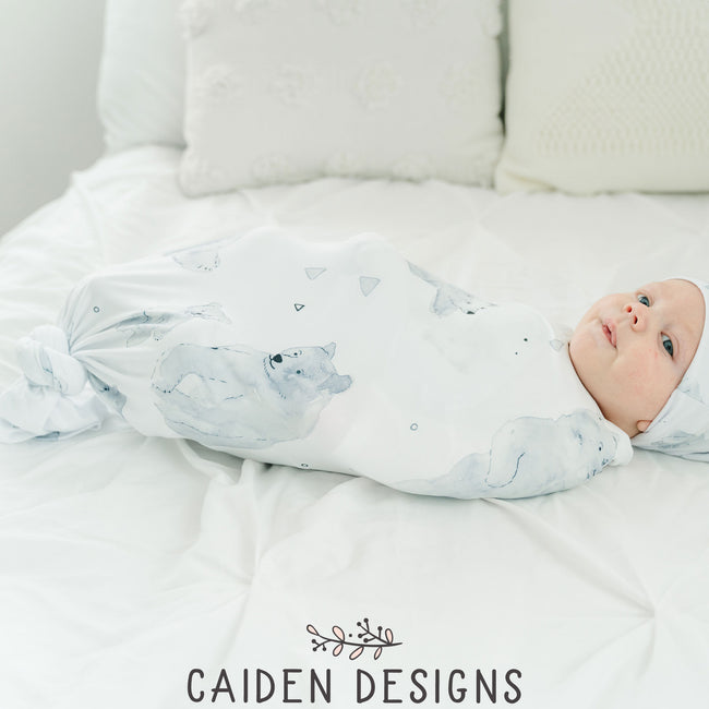 sweet baby wrapped in a monochrome polar bear pattern swaddle blanket and hat set laying on a bed