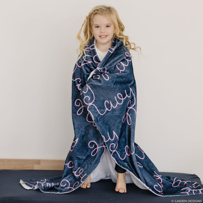 Little girl wrapped in a navy blue personalized blanket with pink name Navy