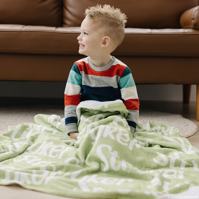 Little boy on the floor with a green personalized blanket