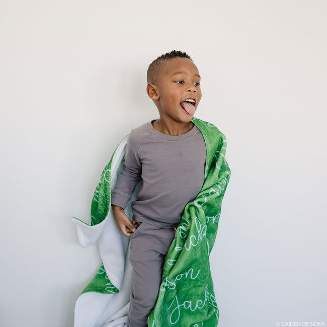 Young boy jumping with a green personalized blanket
