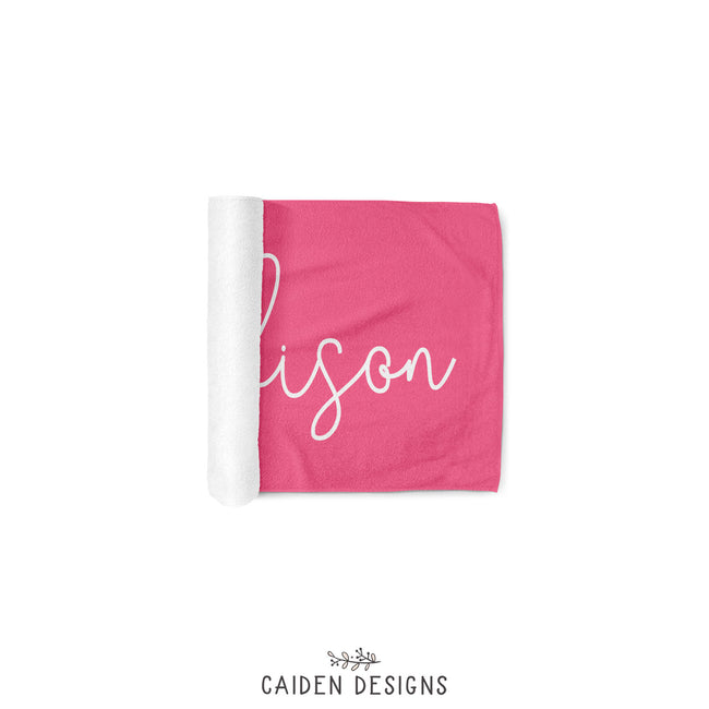 A pink personalized beach towel with the name 'Madison' printed in white on the front. The reverse side is solid white.
