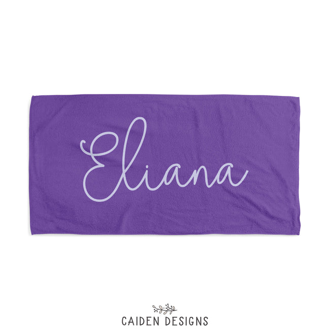A purple personalized beach towel with the name 'Eliana' printed in white on the front. The reverse side is solid white.