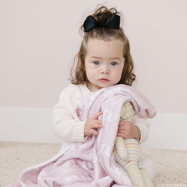 A little girl with a soft pink personalized blanket