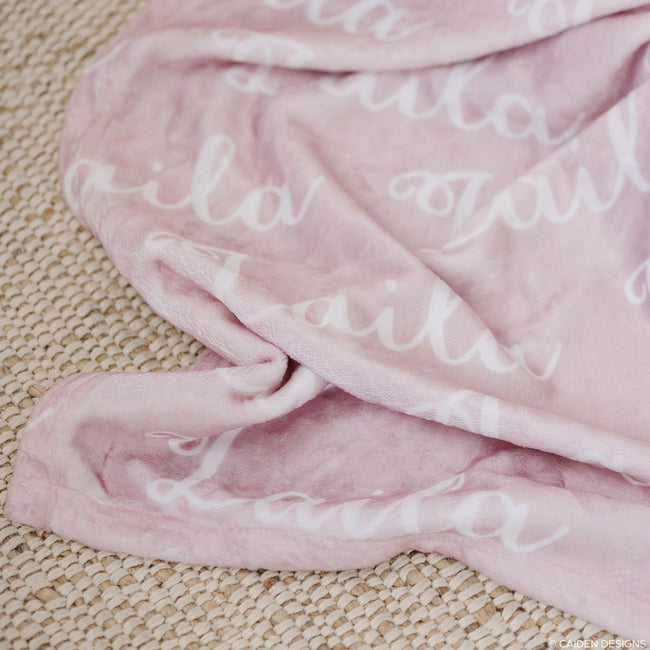 Closeup of a soft pink personalized blanket with a script font