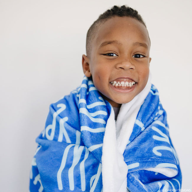 Smiling little boy with a cobalt blue personalized blanket