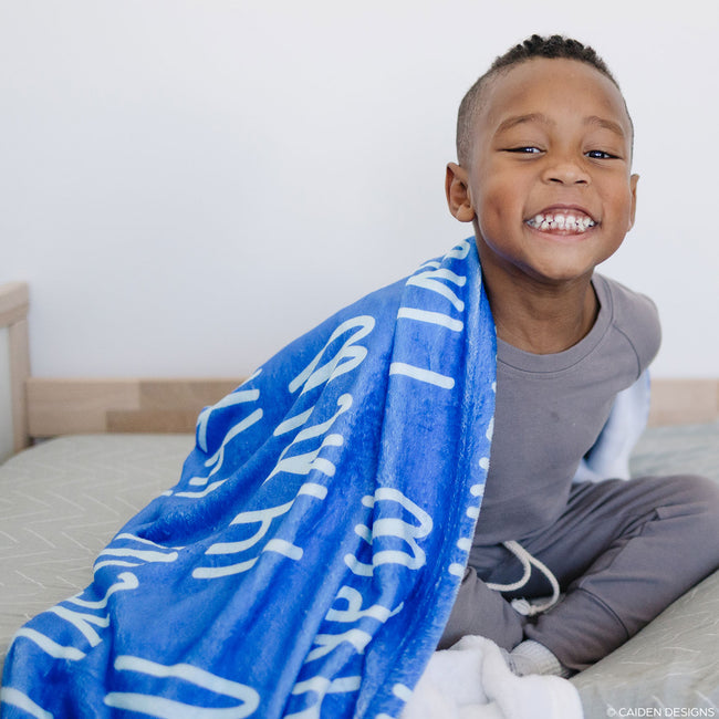 Smiling little boy with a cobalt blue personalized blanket