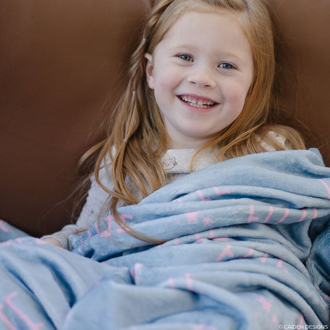 Little girl with a light blue personalized blanket with names on it
