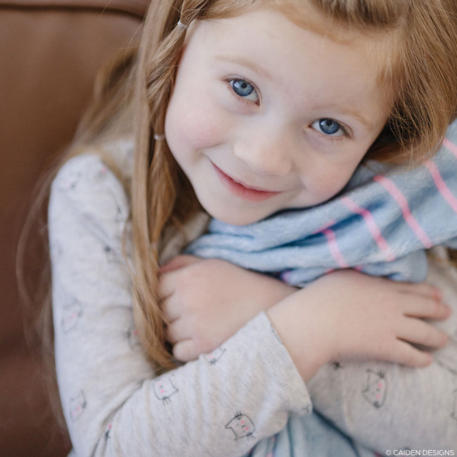 Little girl with a light blue personalized blanket with names on it