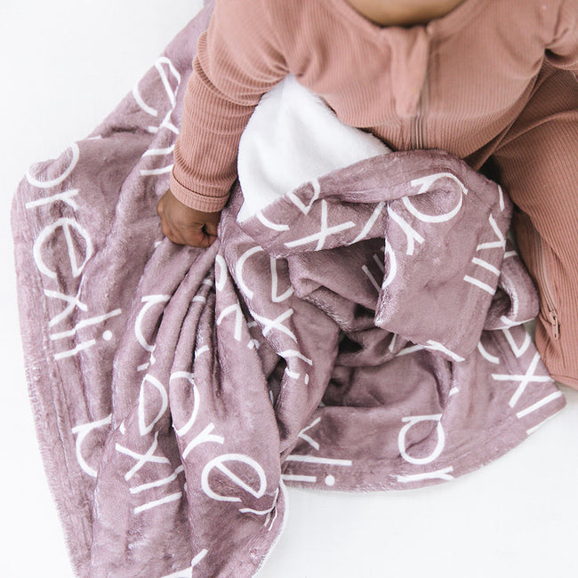 Baby girl with a mauve personalized baby blanket with names