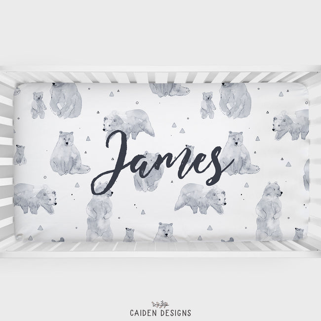 A personalized crib sheet with a watercolor polar bear pattern and the name 'James' printed on it.