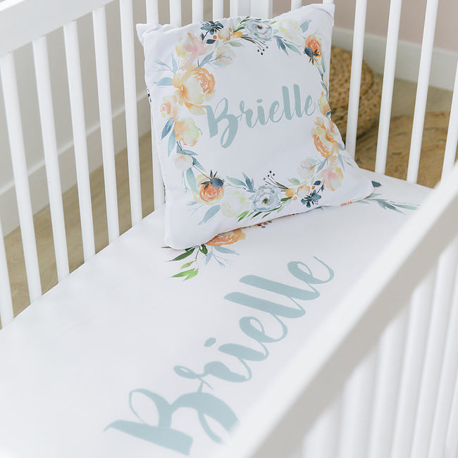 A crib sheet with a floral pattern and the name 'Brielle' printed on it, along with a matching pillowcase.