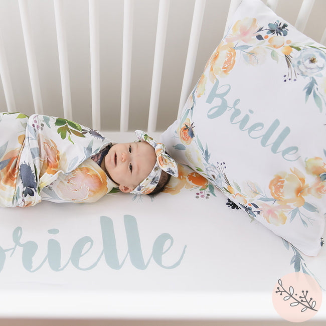 A crib sheet with a floral pattern and the name 'Brielle' printed on it, along with a matching pillowcase.
