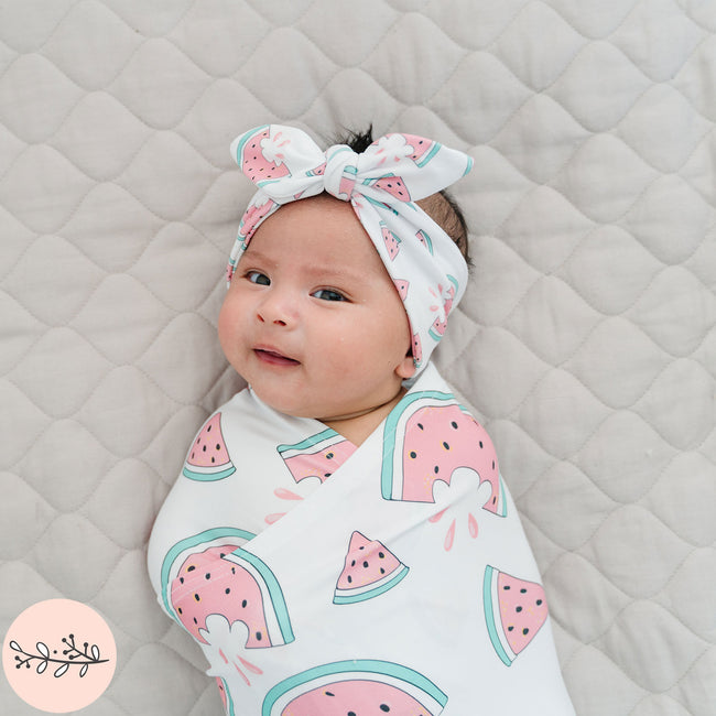 Baby wrapped in a pink watermelon pattern with a matching headband