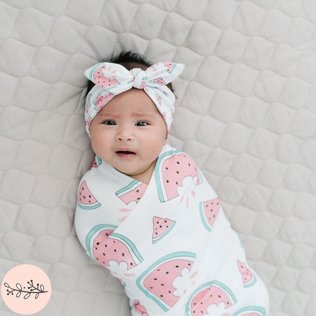 Baby wrapped in a pink watermelon pattern with a matching headband